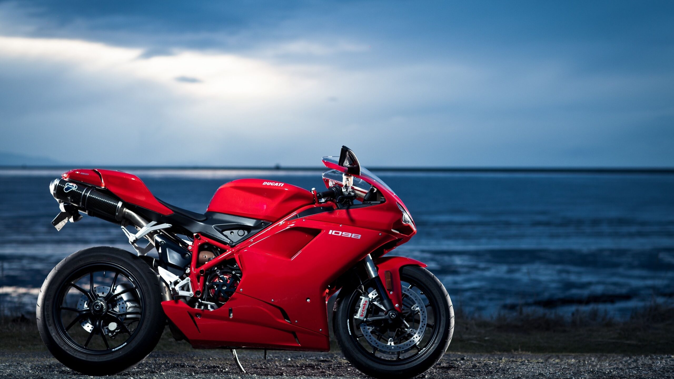 A Red Motorcycle Parked Next To The Ocean